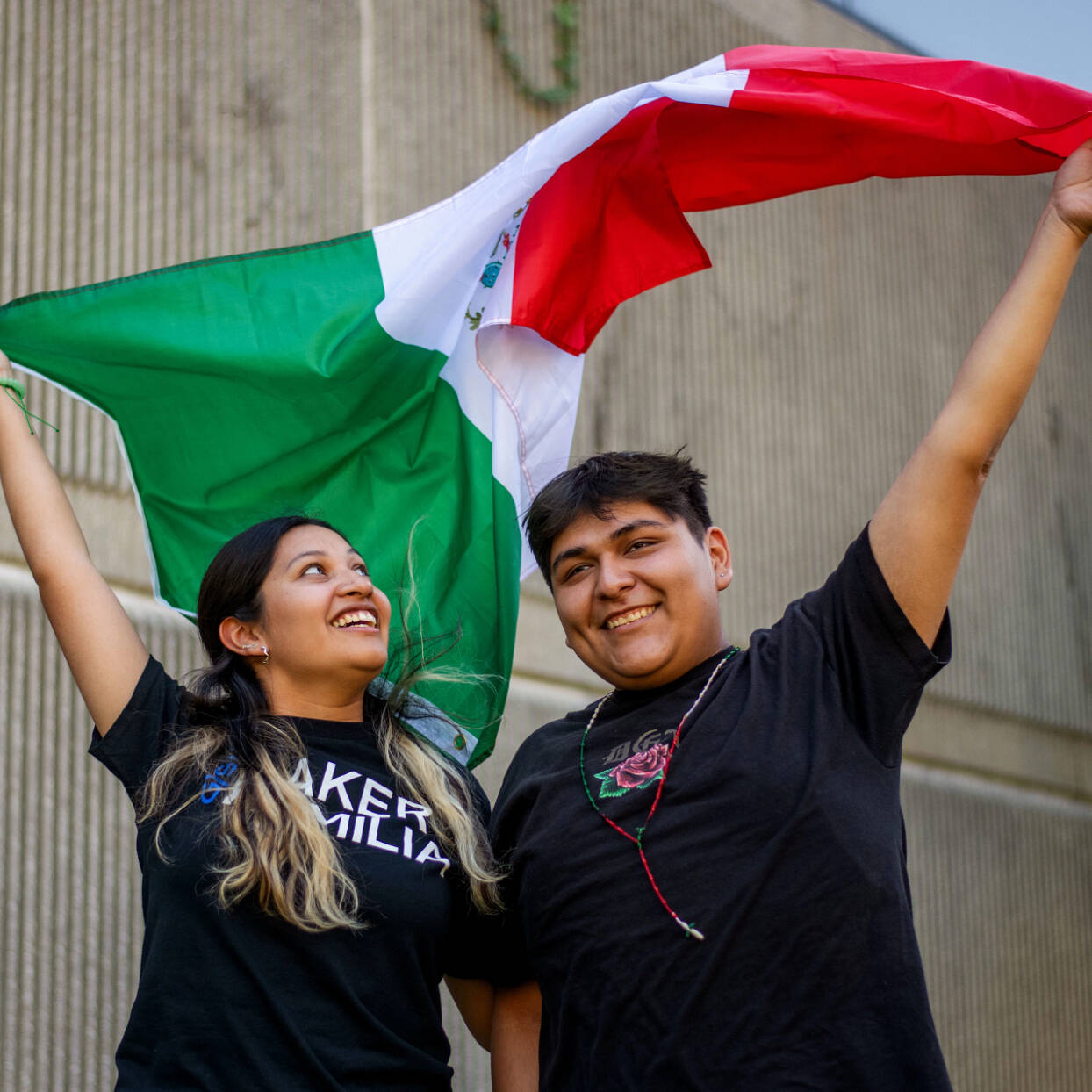 Students and friends Jackelyn Palmas, left, and José Medina, right, laugh together while displaying the Mexican flag.